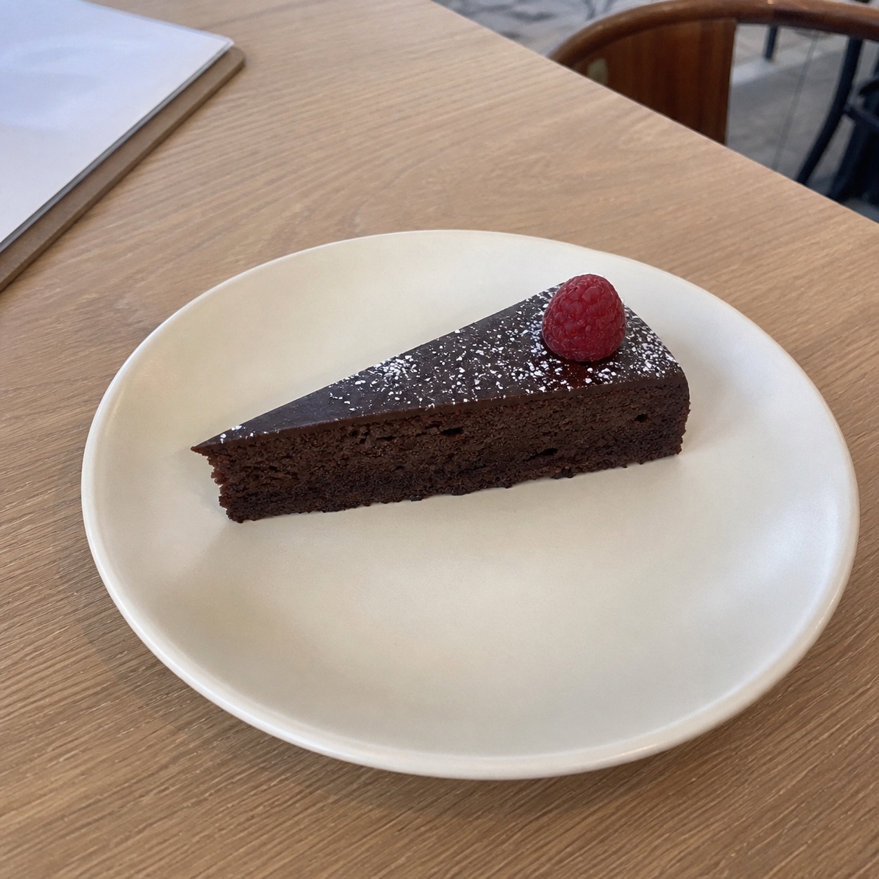 Synthetic source-photo concept of a clean chocolate-cake slice in a café.